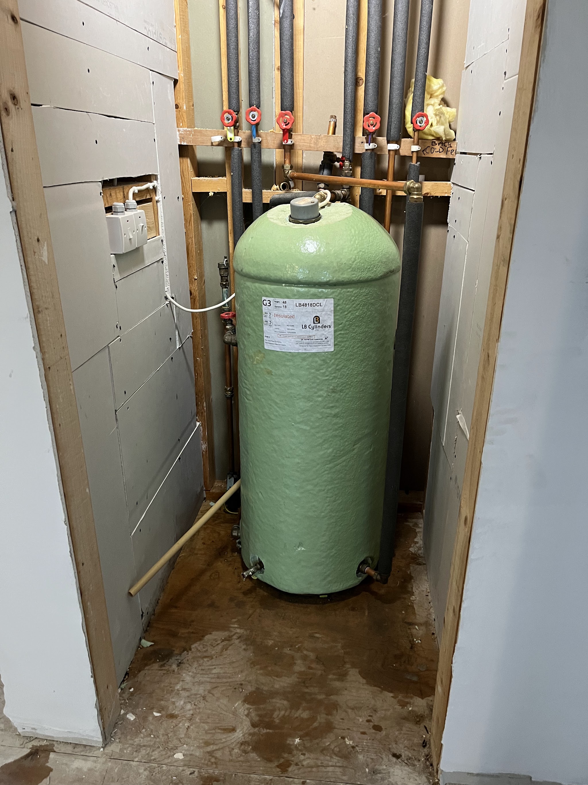Hot water cylinder installed with insulated pipework and valves